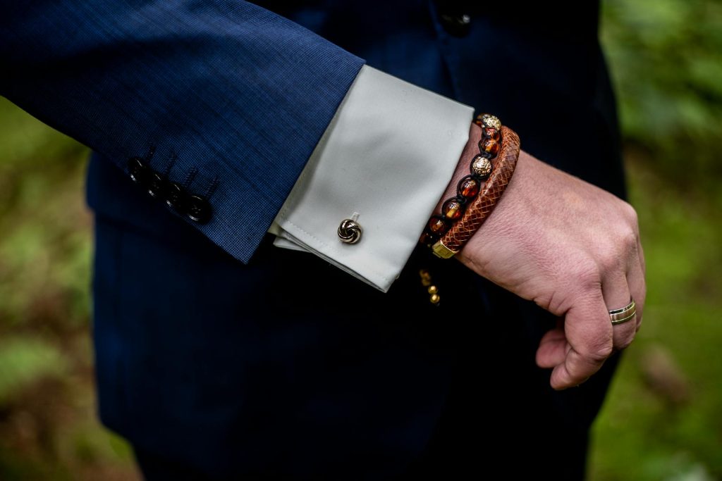 The man in the blue blazer is wearing bracelets.