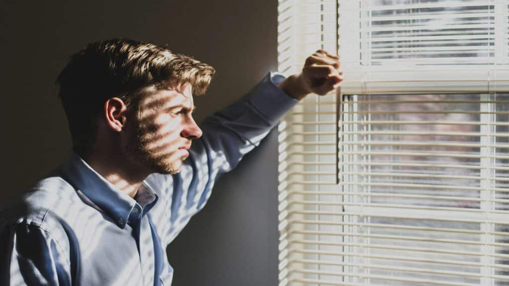 A man looking sad in front of a window.