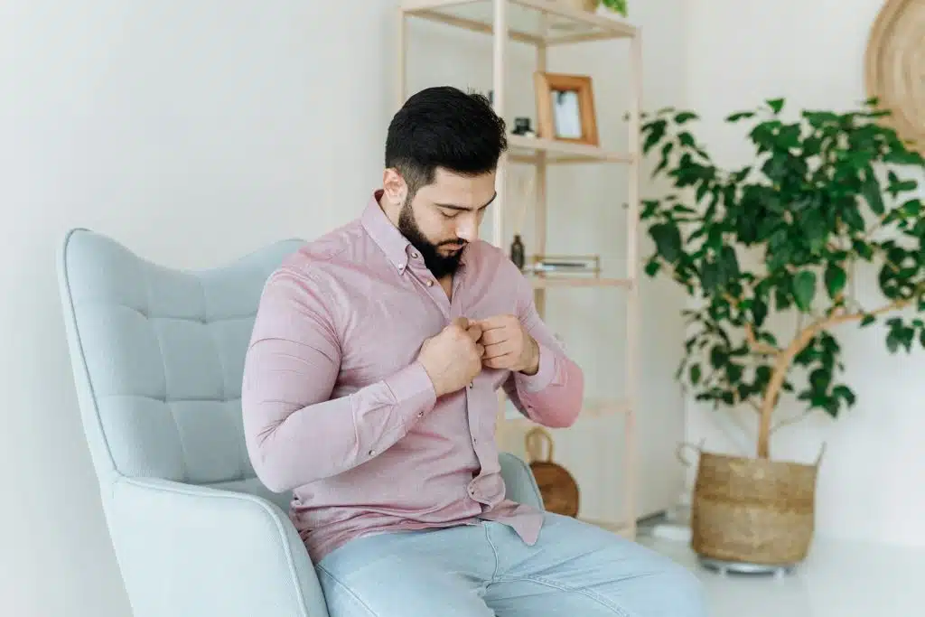 The man is buttoning his shirt.