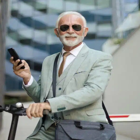 A handsome older man riding a scooter