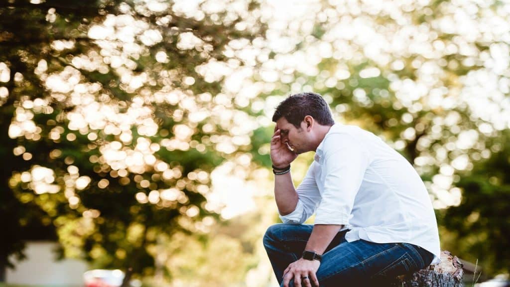 A man looking sad outdoors.