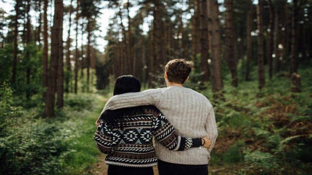 A couple walking in the woods together.