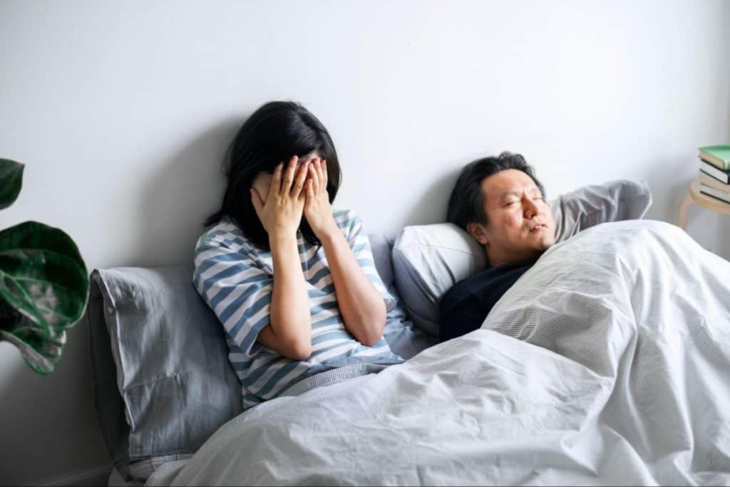 A sad woman beside a sleeping man