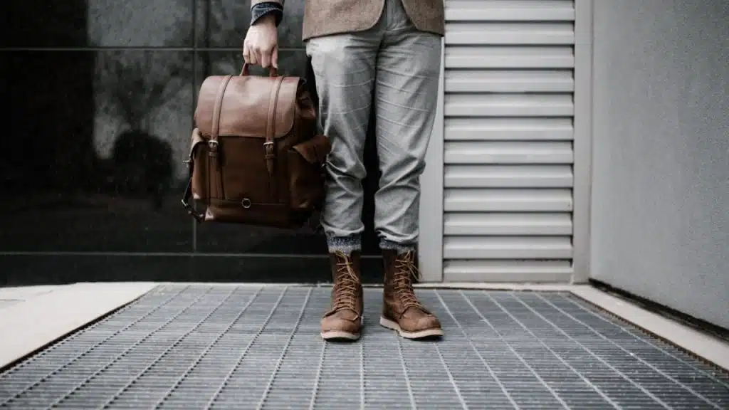 Worn leather boots on man standing holding a leather bag