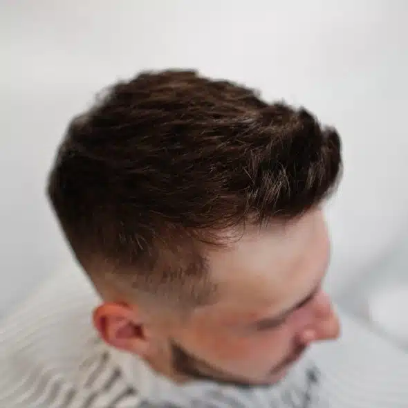 Close up head of young bearded man getting haircut at barbershop